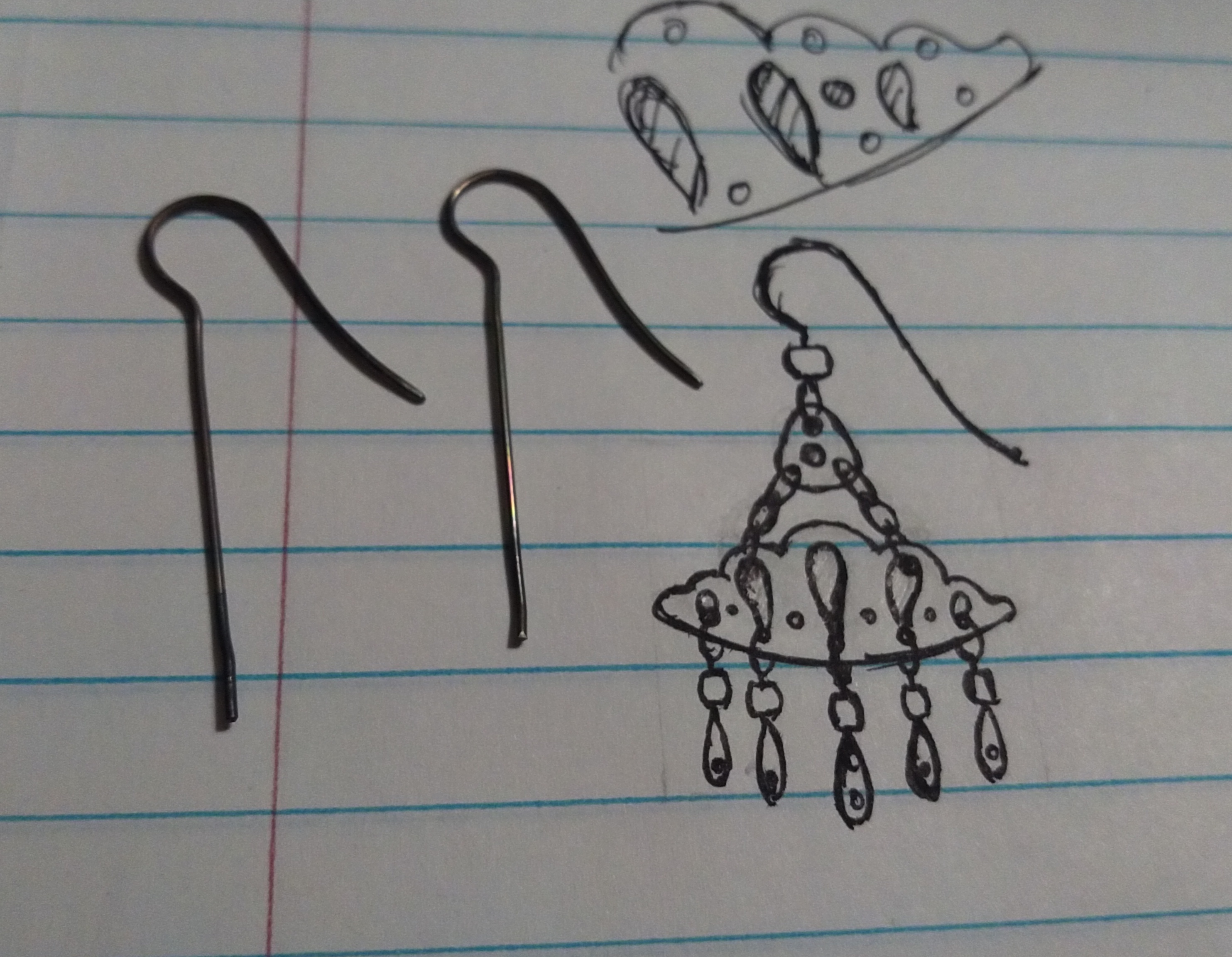 Concept drawing for a pair of pendant earrings shaped like clouds with raindrops. Sitting on the page is a set of partially bent earring hooks.