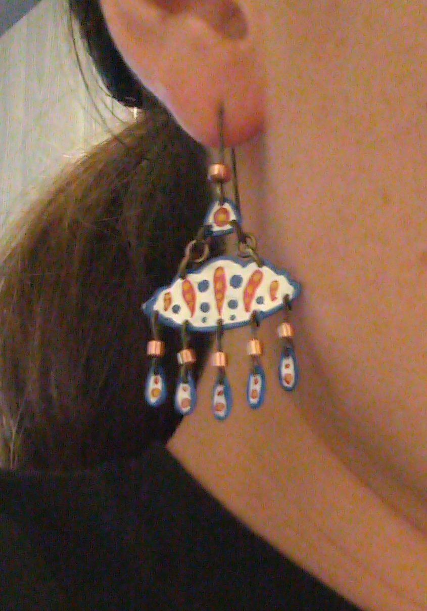 A colorfully ornamented cloud earring on a person's ear