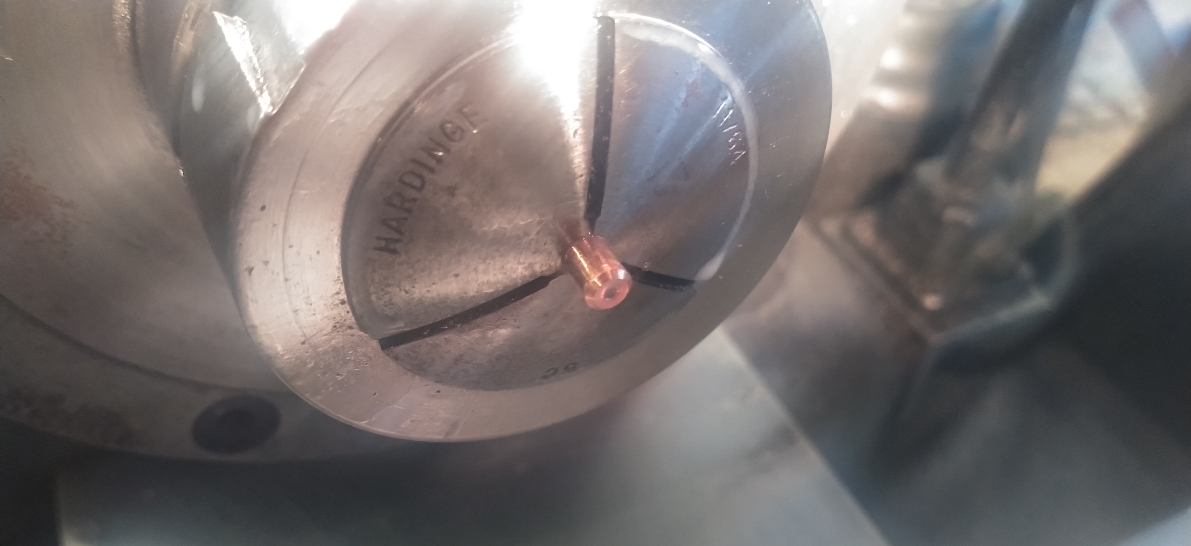 A copper bead being turned on a machine lathe