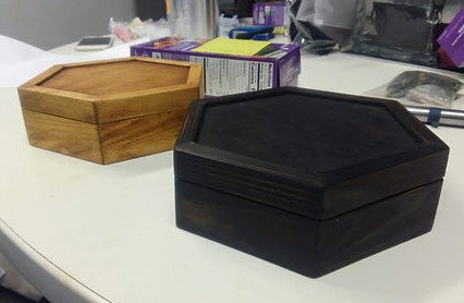 Two hexagonal wooden boxes, one black and one gold