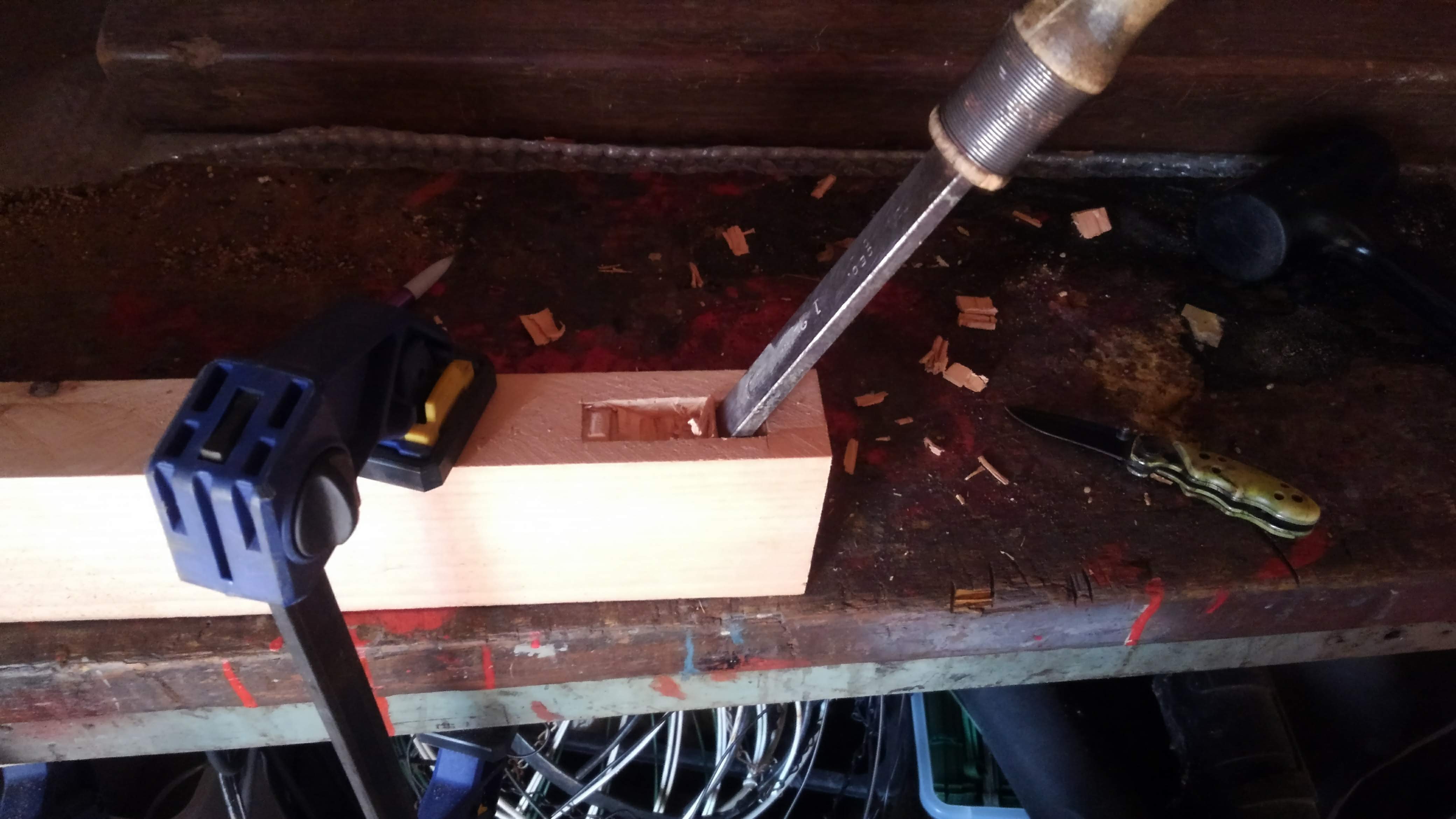 a chisel cutting a mortise in a piece of wood