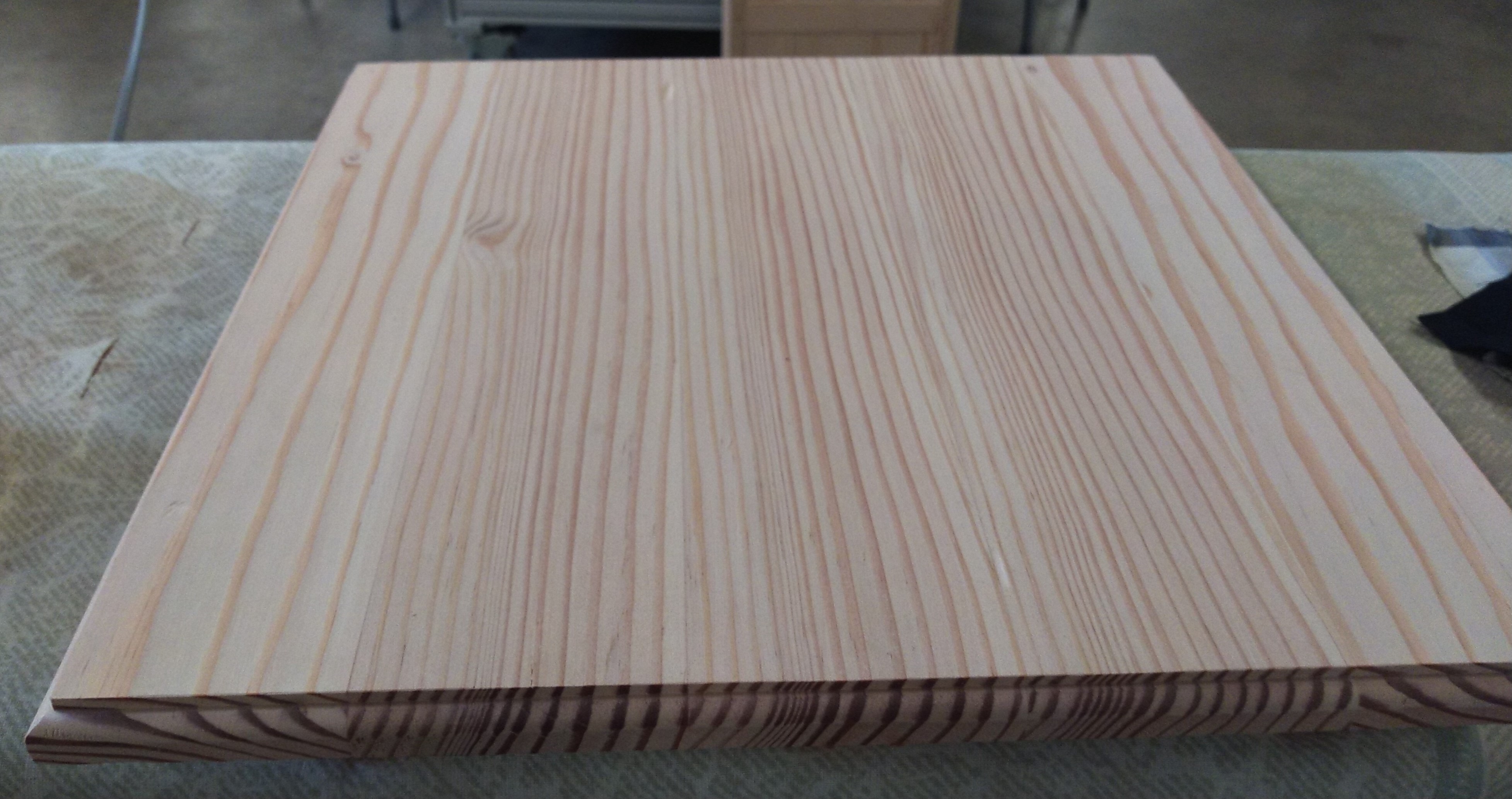 A roughly square piece of wood with a routed profile around the edges