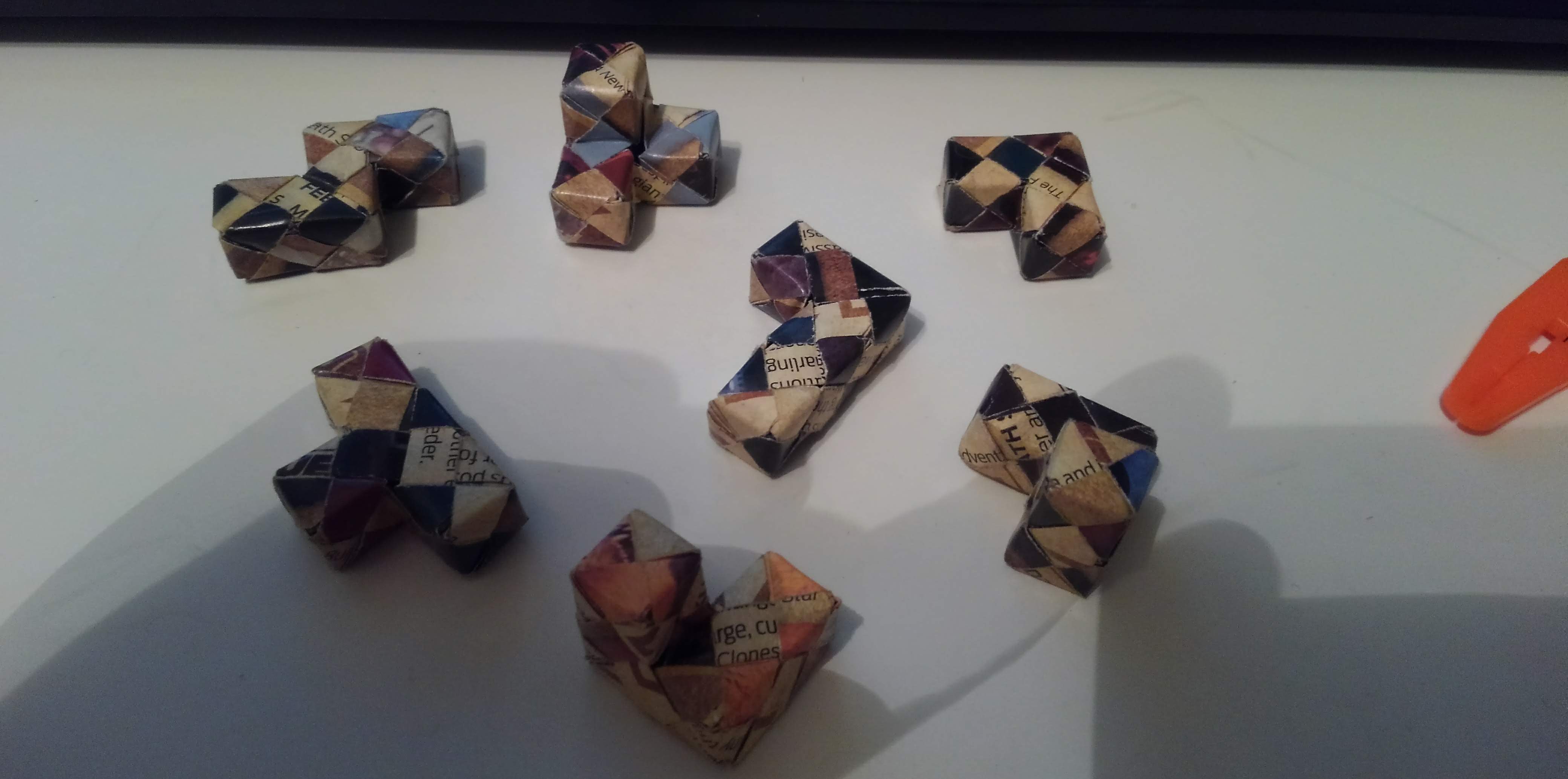 Seven pieces to a sonobe puzzle cube spread out on a table