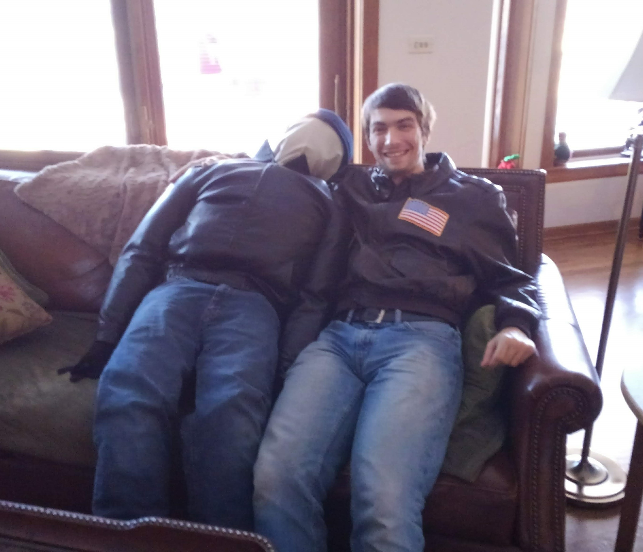 a man and a dummy sitting next to each other on a couch, dressed in similar clothing