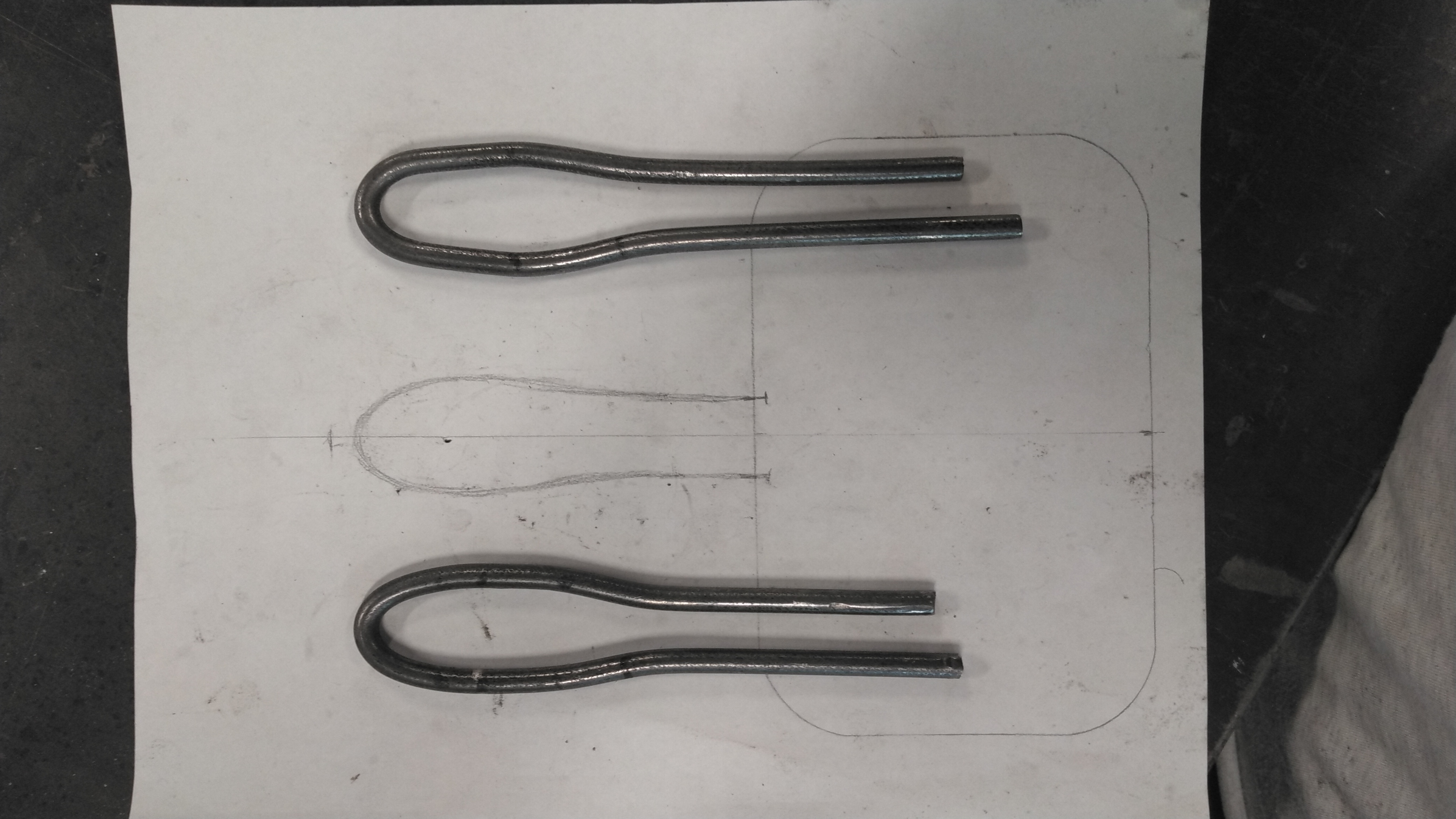 two steel handles being compared to a template