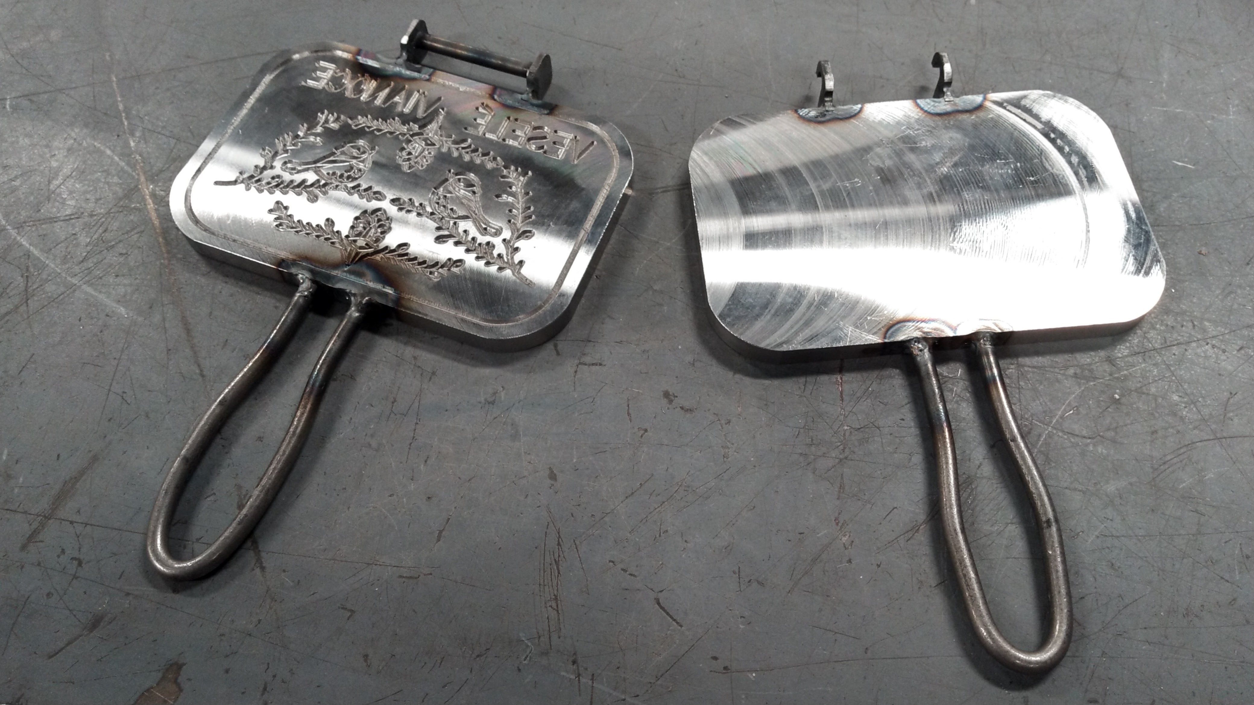 Two sides of a wafer iron with visible heat affected zones from welding